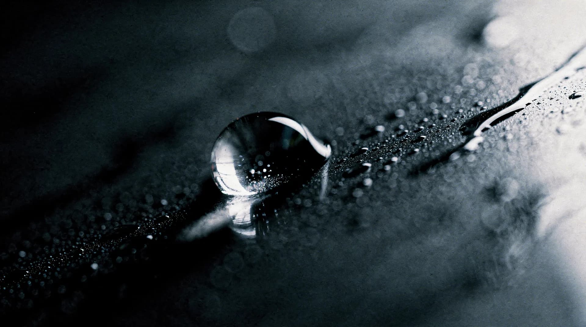 Water droplet on dark stone in hard side light